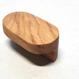 May include: A wooden oval-shaped cabinet knob with a natural wood finish.