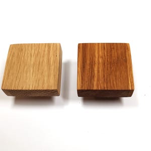 May include: Two square wooden knobs, one is a natural wood colour and the other is stained a darker brown.