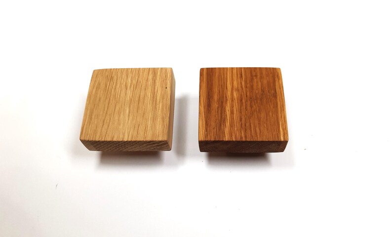 May include: Two square wooden knobs, one is a natural wood colour and the other is stained a darker brown.