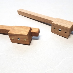 以下が含まれることがあります： 正方形の形状と長方形のハンドルを持つ木製の引き出しノブ2つ。ノブにはそれぞれ小さなネジが3つあります。