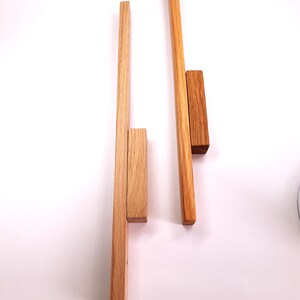 May include: Two wooden dowels with a smaller wooden block attached to each. The dowels are about 12 inches long and the blocks are about 2 inches long.
