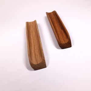 May include: Two wooden trays, one light brown and one dark brown, with a curved shape and a groove running down the center.