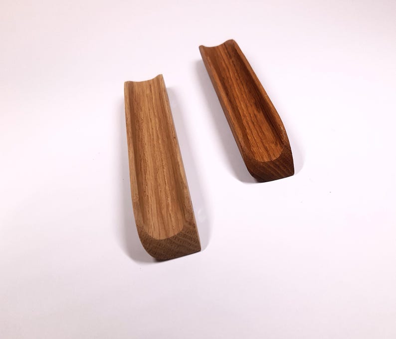 May include: Two wooden trays, one light brown and one dark brown, with a curved shape and a groove running down the center.