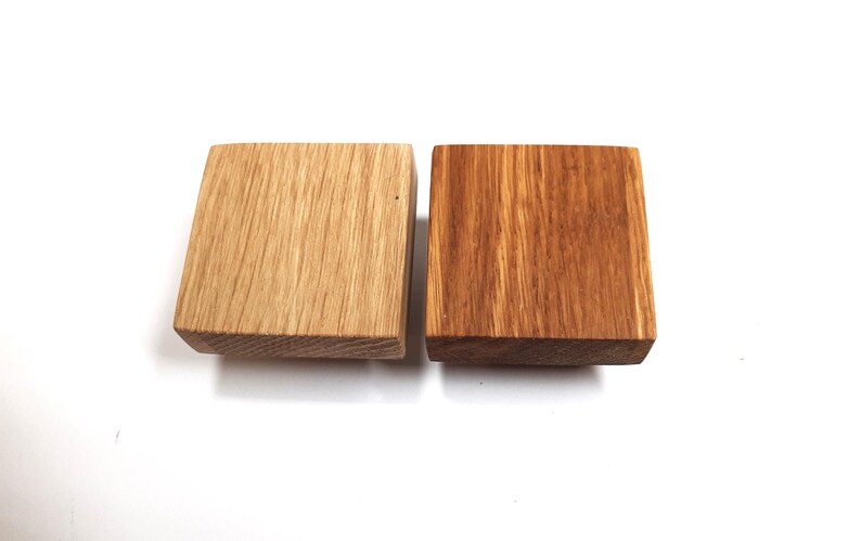 May include: Two square wooden knobs, one is a natural wood colour and the other is stained a darker brown.