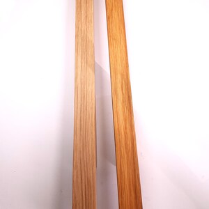 May include: Two wooden strips, one light brown and one darker brown, side by side. Both strips have a wood grain pattern.