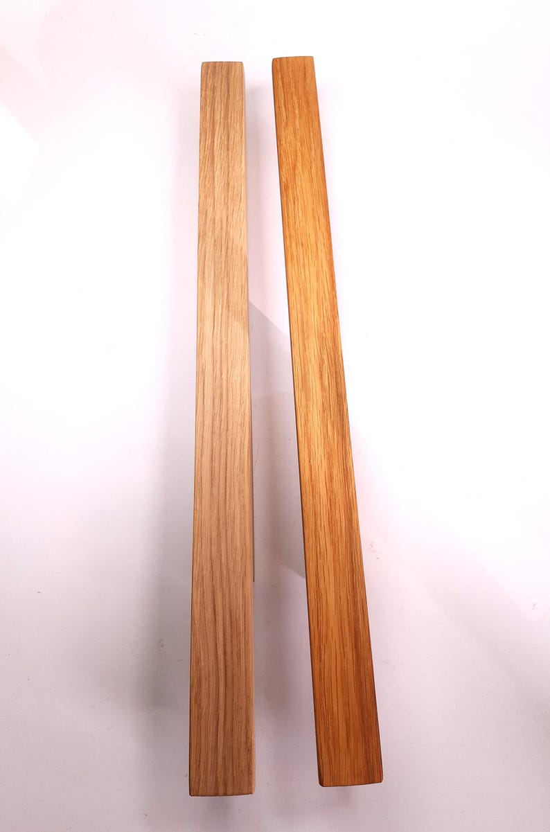 May include: Two wooden strips, one light brown and one darker brown, side by side. Both strips have a wood grain pattern.