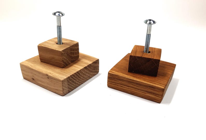 May include: Two wooden wall hooks with a screw in the centre. The hooks are made of natural wood with a light brown finish. The hooks are stacked on top of each other.