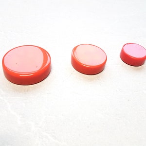 Könnte beinhalten: Drei runde, orangefarbene Plastikdeckel in verschiedenen Größen.