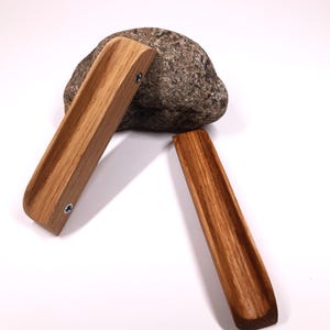 May include: Two wooden drawer pulls with a curved design. The pulls are made of light brown wood with a natural grain pattern. The pulls are shown on a white background.