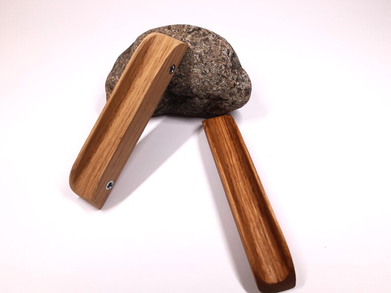 May include: Two wooden drawer pulls with a curved design. The pulls are made of light brown wood with a natural grain pattern. The pulls are shown on a white background.