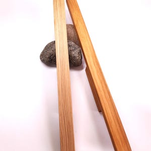 May include: Two wooden cabinet pulls with a natural wood finish. The pulls are rectangular in shape and have rounded edges.
