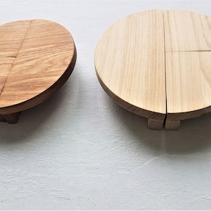 May include: Two round wooden coasters, one with a natural wood finish and the other with a darker, more reddish brown finish. Both coasters are made of four pieces of wood that are joined together to form a circle.