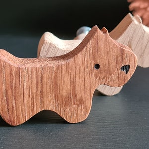 Könnte beinhalten: Drei Haken aus Holz in Form eines Hundes, jeder mit einem anderen Holzmaserungsmuster. Die Haken sind braun und haben eine natürliche Oberfläche.