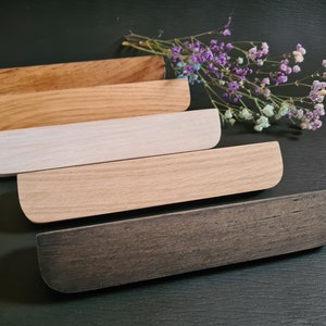 Peut inclure: Cinq plateaux en bois de différentes nuances de brun, blanc et noir. Les plateaux sont empilés les uns sur les autres, le plateau le plus foncé en bas et le plateau le plus clair en haut.