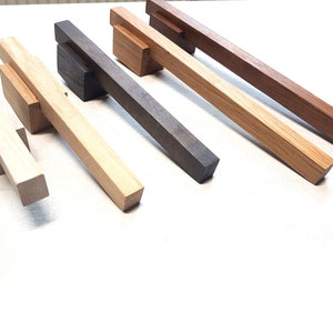 Puede incluir: Cinco tiradores de puerta de armario de madera en diferentes acabados de madera. Los tiradores están hechos de madera maciza y tienen un diseño simple y moderno.