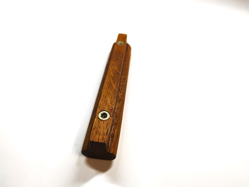May include: A long, rectangular wooden handle with a rich brown grain pattern. The handle features two circular metal inserts with screw holes positioned along its length, providing a secure mounting point for attachment to a cabinet or drawer.