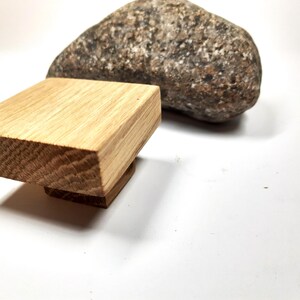 May include: A square wooden knob with a light brown finish. The knob is made of solid wood and has a smooth, polished surface.