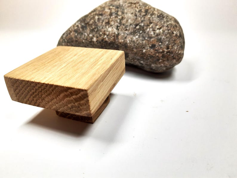 May include: A square wooden knob with a light brown finish. The knob is made of solid wood and has a smooth, polished surface.