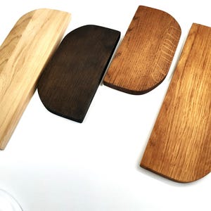 Puede incluir: Cuatro tablas de cortar de madera en diferentes tonos de marrón, incluyendo natural, marrón oscuro y marrón claro. Las tablas son todas rectangulares con bordes redondeados.