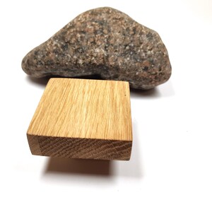 May include: A square wooden block with a natural wood grain finish. The block is made of oak and has a smooth surface. It is sitting on a white background.