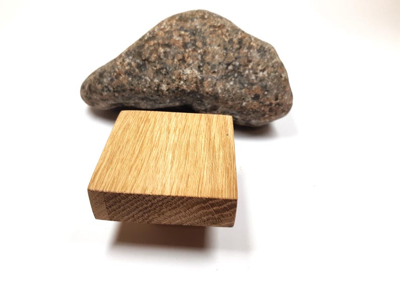 May include: A square wooden block with a natural wood grain finish. The block is made of oak and has a smooth surface. It is sitting on a white background.