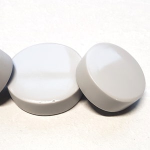 May include: Three round, white ceramic knobs with a smooth, glossy finish.