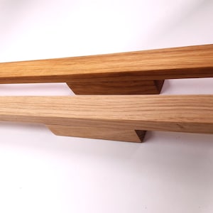 May include: Two wooden drawer pulls in different shades of brown. The pulls are rectangular with a slight curve on the top and bottom.