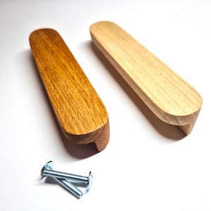 May include: Two elongated wooden drawer pulls with rounded ends, one featuring a medium brown wood grain and the other a lighter natural wood finish, accompanied by two silver-colored metal screws with flat heads and threaded shafts.