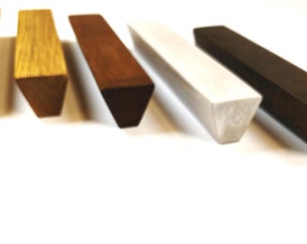 Puede incluir: Cinco tiradores de cajón de madera alargados con sección transversal triangular, dispuestos en fila. El conjunto incluye varios tonos de madera que van desde el roble natural claro, marrón medio, blanqueado, hasta un acabado espresso oscuro.