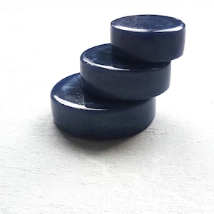 May include: Four round, blue, glossy, decorative coasters stacked on top of each other.