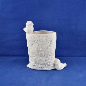 May include: White ceramic planter shaped like a bag of sunflower seeds with two small birds perched on the top and side. The bag has the words "Sunflower Seeds" and "Bird Seed" embossed on the front.