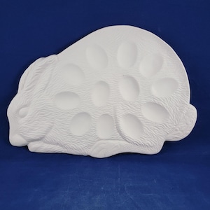 May include: White ceramic bunny-shaped egg holder with six egg-shaped indentations.