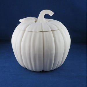May include: White ceramic pumpkin shaped candy dish with a lid. The lid has a small leaf detail on top.