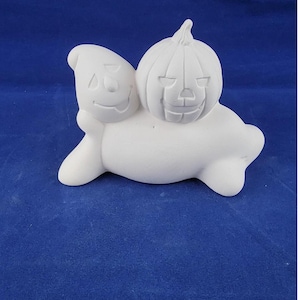 May include: White ceramic figurine of a ghost with a jack-o'-lantern pumpkin on its back. The ghost has a friendly face and the pumpkin has a carved grin.