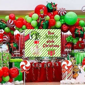 May include: A festive Christmas party scene with red, green, and white decorations. The centerpiece features a sign that reads "How Jessie stole Christmas" with a baby in a Christmas ornament. Balloons, gifts, and candy canes complete the holiday theme.