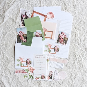 Può includere: Una collezione di articoli di cancelleria con illustrazioni di rose. Include buste, adesivi e biglietti con disegni floreali e testo. La tavolozza dei colori è tenue, con toni rosa, verdi e crema, creando un'estetica romantica e vintage.