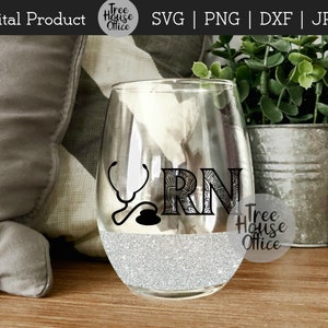 May include: A clear glass wine glass with a silver glitter design. The glass has a black and white design of a stethoscope and the letters "RN" with a decorative pattern. The text "Tree House Office" is visible on the glass.