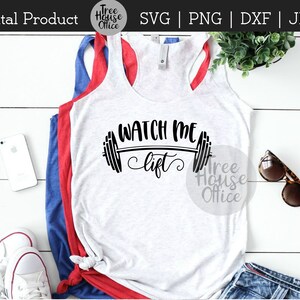 Puede incluir: Una camiseta sin mangas blanca con el texto "WATCH ME lift" en letras negras y un gr&aacute;fico de barra de pesas. La camiseta sin mangas est&aacute; superpuesta sobre una camiseta sin mangas azul y una camiseta sin mangas roja.