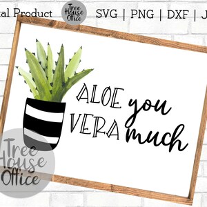 May include: A white sign with a wooden frame features a watercolor illustration of an aloe vera plant in a black and white striped pot. The text "ALOE you VERA much" is written in black cursive font.