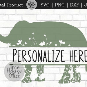 May include: A green silhouette of an elephant with white flowers growing from its back. The elephant is standing on a white brick background. The text "PERSONALIZE HERE" is written in black on a white banner below the elephant.