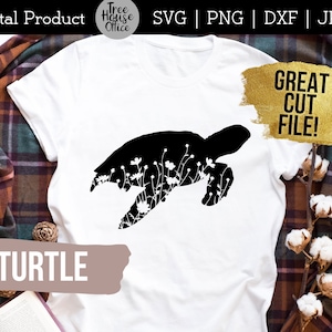 Puede incluir: Una camiseta blanca con una silueta negra de una tortuga con detalles florales. El texto "TURTLE" está impreso en marrón en la parte inferior de la camiseta. El texto "GREAT CUT FILE!" está impreso en dorado sobre un fondo amarillo.