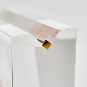 May include: A clear acrylic display stand with a gold metal accent at the top.