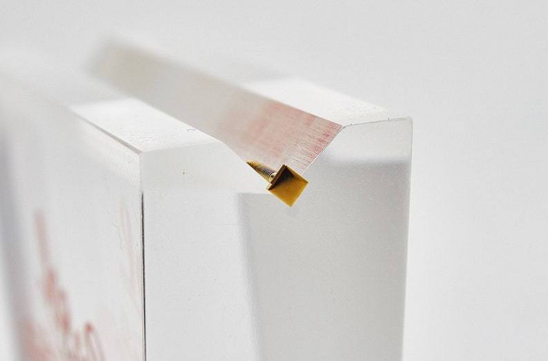 May include: A clear acrylic display stand with a gold metal accent at the top.