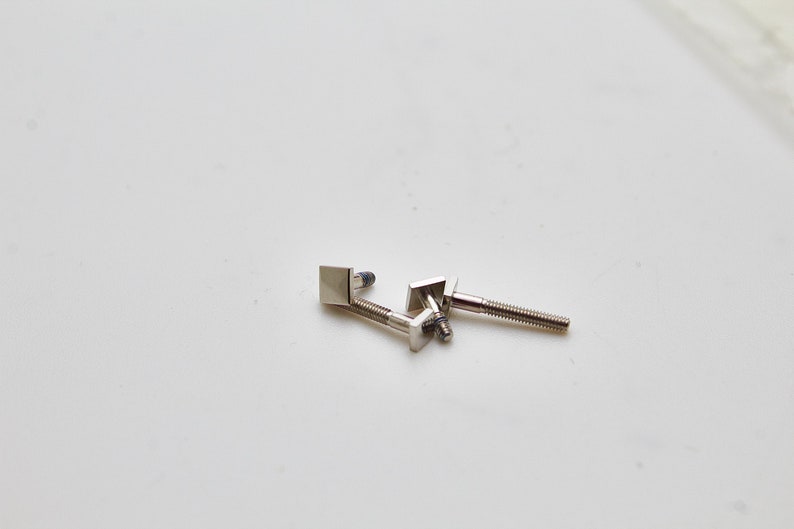 May include: Three silver metal screws with square heads