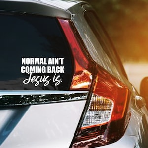 Puede incluir: Una calcoman&iacute;a de vinilo blanca en la ventana de un coche con el texto "NORMAL AIN'T COMING BACK Jesus is." La calcoman&iacute;a est&aacute; en la ventana trasera de un coche plateado.