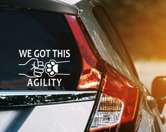 Puede incluir: Un coche plateado con una pegatina de vinilo blanco que dice "We Got This Agility" con una huella de pata y dos manos chocando los cinco.