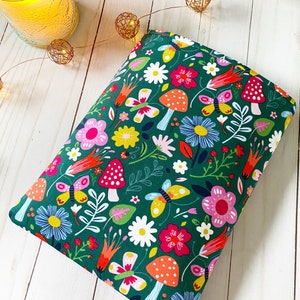 May include: A green fabric pouch with a colorful floral and butterfly print. The pouch is filled with a soft, plush material and is perfect for adding a touch of whimsy to any room.