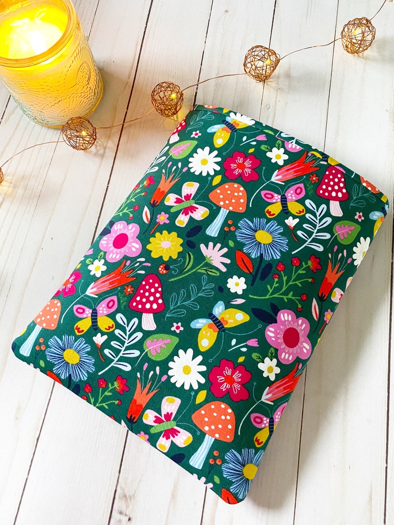 May include: A green fabric pouch with a colorful floral and butterfly print. The pouch is filled with a soft, plush material and is perfect for adding a touch of whimsy to any room.