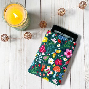 Op de afbeelding: Een groene e-reader hoes met een bloemen- en paddenstoelpatroon. De hoes heeft verschillende kleuren, waaronder rood, roze, geel en blauw.