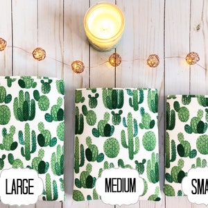 May include: Three cactus-patterned book covers in different sizes: large, medium, and small. The covers are white with green cactus illustrations.